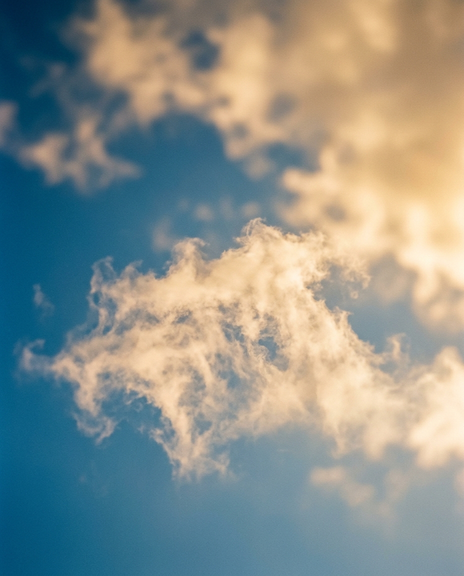 Cinematic film still of blue sky with soft clouds, close-up detail with shallow depth of field, warm golden light, calm mood, 4:5 aspect ratio