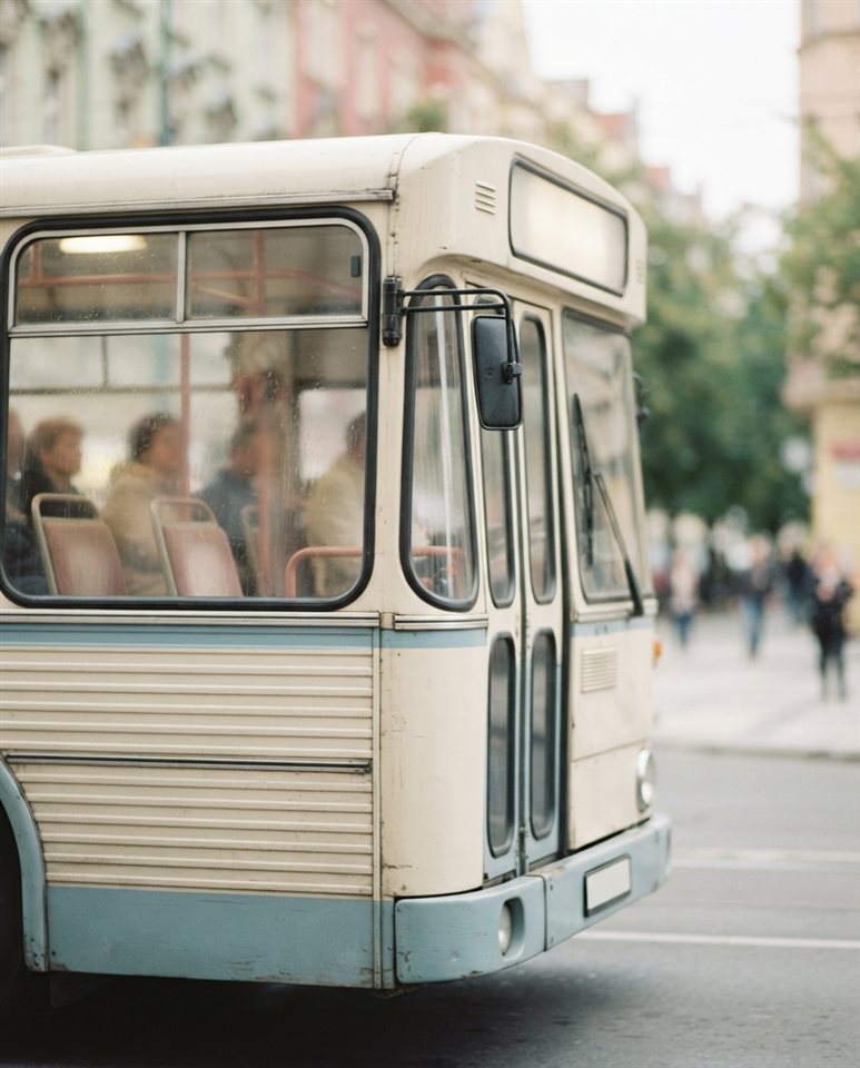 Cinematic film still of a city bus on a street, close-up detail with shallow depth of field, soft pastel colors, bright and cozy, 4:5 aspect ratio