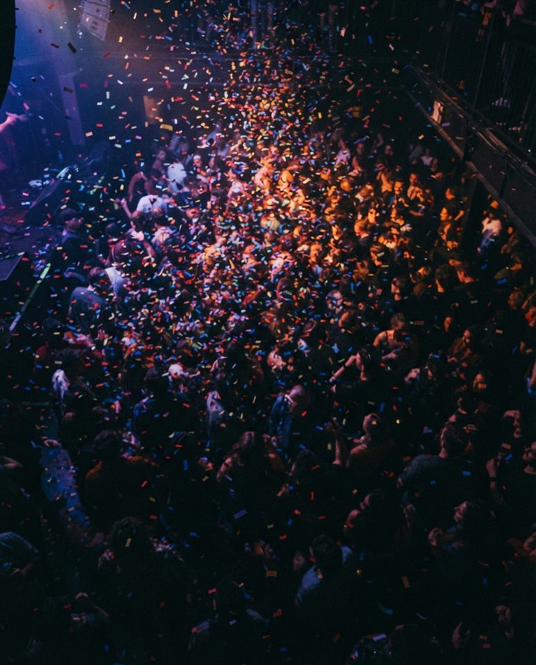 Cinematic film still of colorful confetti falling, high-angle view from above, moody dark tones, dramatic lighting, 4:5 aspect ratio