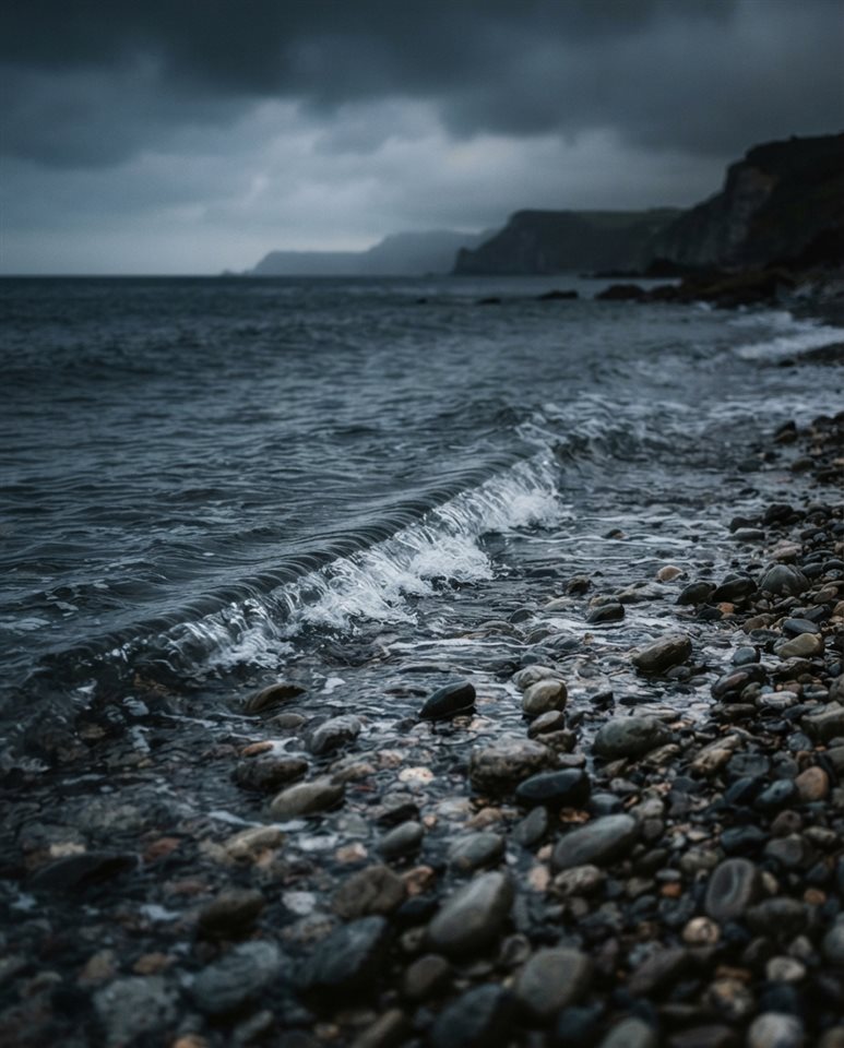Photorealistic photo of a calm wave touching a quiet pebble shore, centered subject with a simple uncluttered composition, moody dark tones, dramatic lighting, 4:5 aspect ratio
