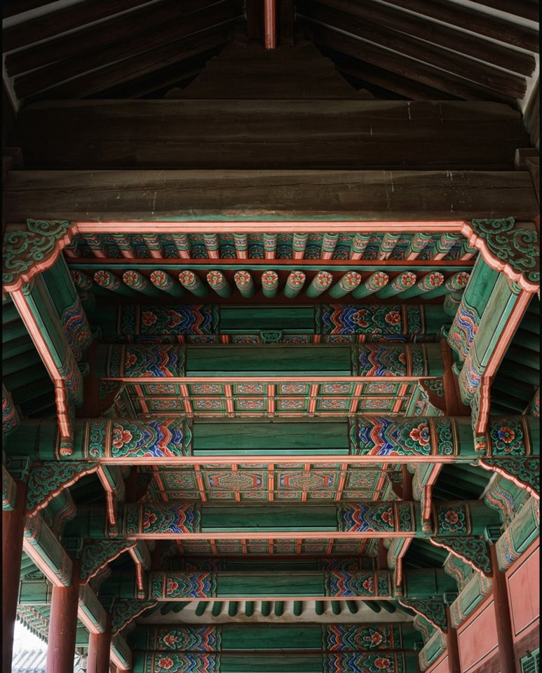 Cinematic film still of a seamless traditional Korean dancheong pattern in red, green and blue, wide shot with open space at the top for text, vivid colors, high contrast, energetic, 4:5 aspect ratio