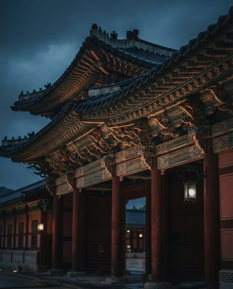 Photorealistic photo of a grand traditional Korean palace gate with colorful dancheong patterns, close-up detail with shallow depth of field, moody dark tones, dramatic lighting, 4:5 aspect ratio