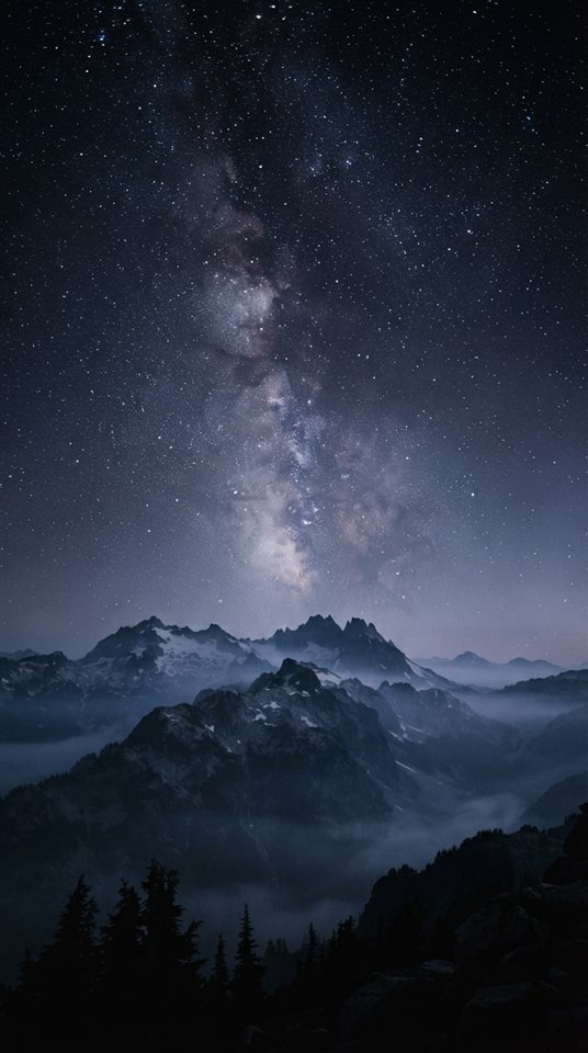Cinematic film still of milky way over mountains, wide shot with open space at the top for text, misty morning haze, dreamy, 9:16 aspect ratio
