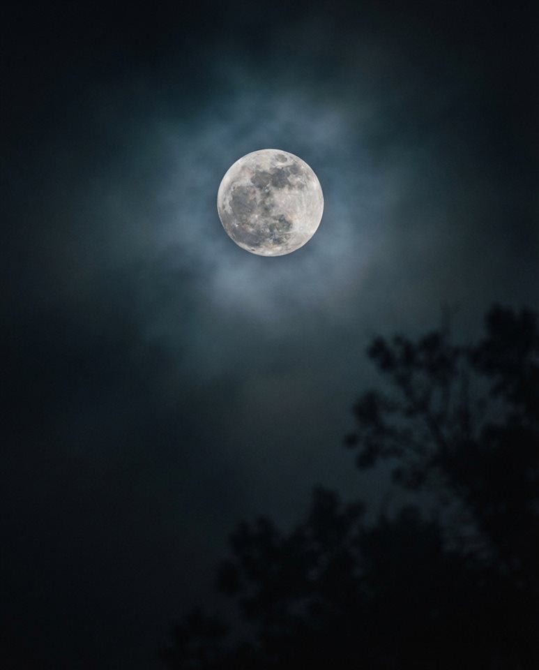 Cinematic film still of full moon in the night sky, close-up detail with shallow depth of field, misty morning haze, dreamy, 4:5 aspect ratio