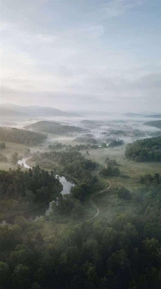 Photorealistic photo of calm minimal landscape with plenty of empty space for text, high-angle view from above, misty morning haze, dreamy, 9:16 aspect ratio