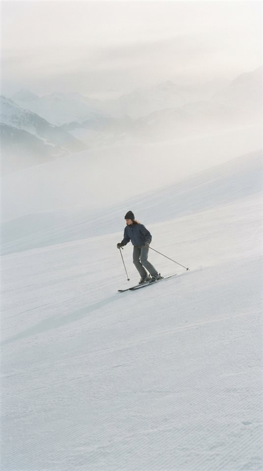 Cinematic film still of a snowy ski slope, centered subject with a simple uncluttered composition, misty morning haze, dreamy, 9:16 aspect ratio