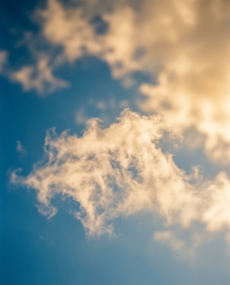 帶有柔軟雲朵的藍天電影劇照，淺景深的特寫細節，溫暖金光，平靜氛圍，4:5 比例