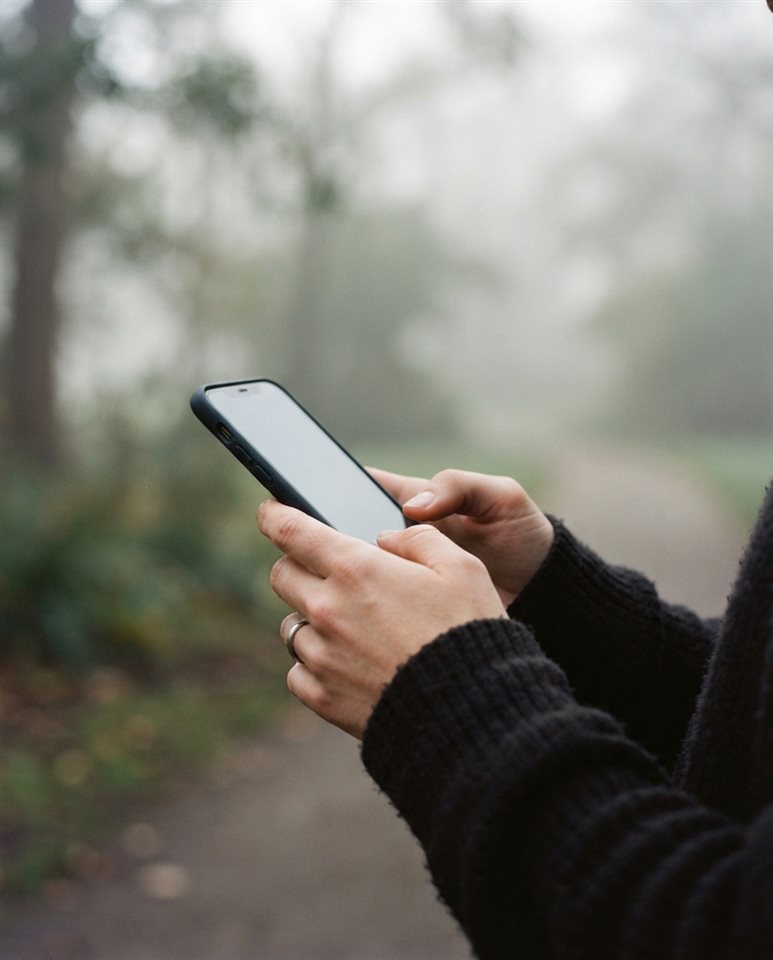 Cinematic film still of smartphone in hand, close-up detail with shallow depth of field, misty morning haze, dreamy, 4:5 aspect ratio