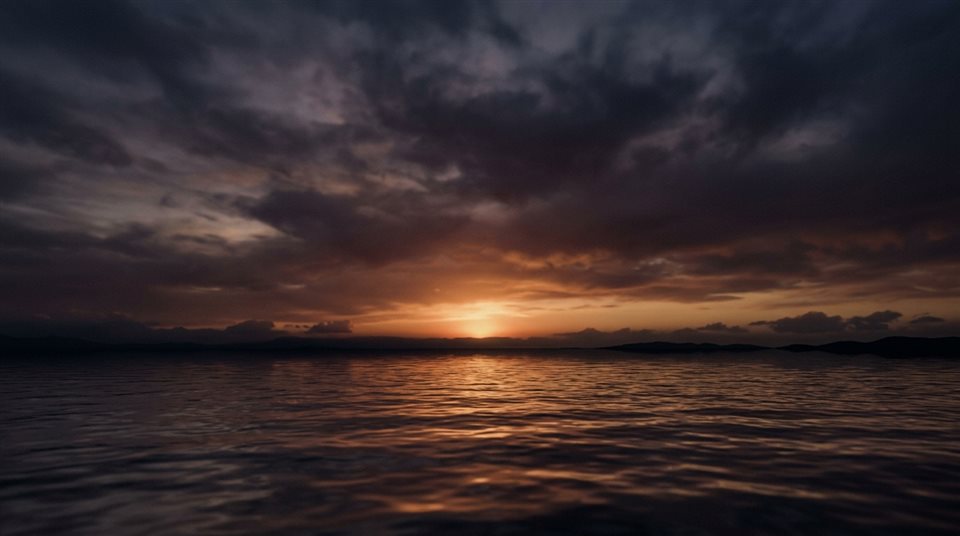 Renderização 3D suave de pôr do sol sobre o mar, tomada ampla com espaço livre na parte superior para texto, tons escuros melancólicos, iluminação dramática, proporção 16:9
