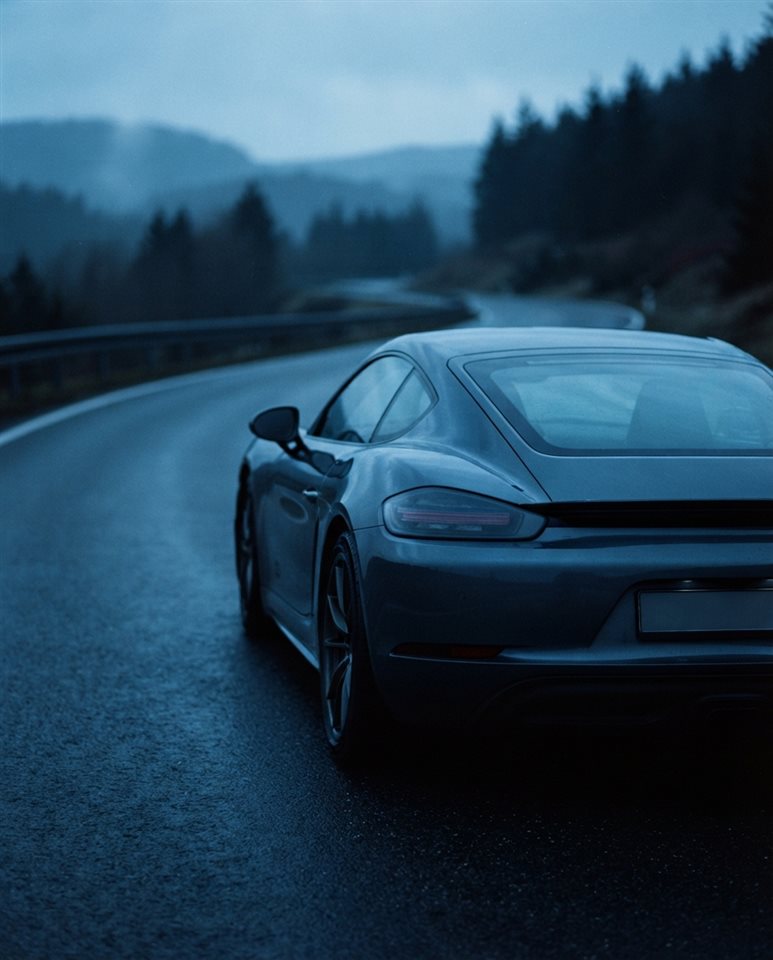 Cinematic film still of sleek generic sports car on an empty road, no brand badges, close-up detail with shallow depth of field, cool blue tones, quiet atmosphere, 4:5 aspect ratio