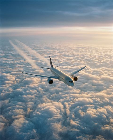 Cinematic film still of an airplane flying above the clouds, high-angle view from above, misty morning haze, dreamy, 4:5 aspect ratio
