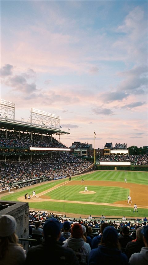 Cinematic film still of a baseball stadium at night, wide shot with open space at the top for text, soft pastel colors, bright and cozy, 9:16 aspect ratio