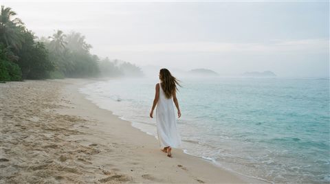 Photorealistic photo of sandy beach with clear turquoise water, centered subject with a simple uncluttered composition, misty morning haze, dreamy, 16:9 aspect ratio