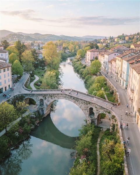 Cinematic film still of bridge over a river, high-angle view from above, soft pastel colors, bright and cozy, 4:5 aspect ratio