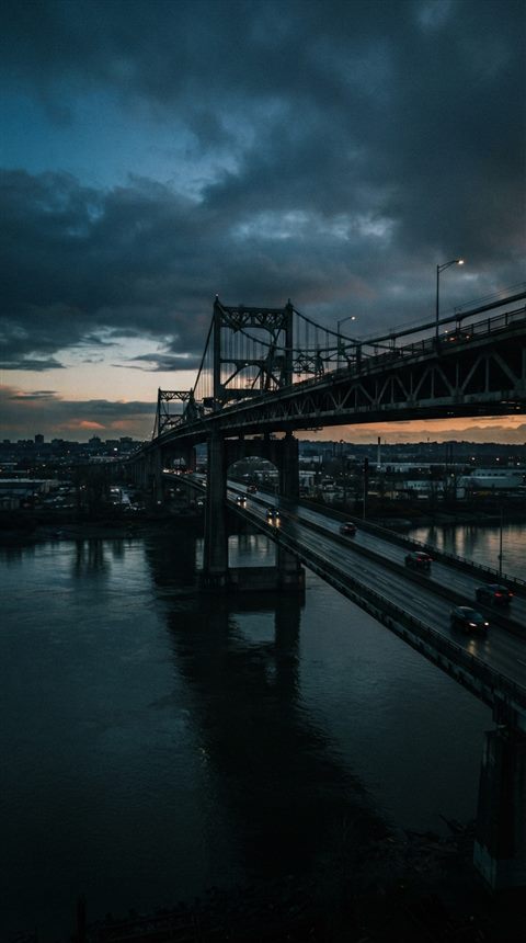 Cinematic film still of bridge over a river, wide shot with open space at the top for text, moody dark tones, dramatic lighting, 9:16 aspect ratio