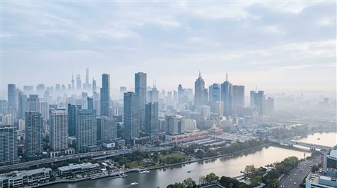 Photorealistic photo of modern city skyline, wide shot with open space at the top for text, misty morning haze, dreamy, 16:9 aspect ratio