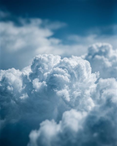 Cinematic film still of fluffy white clouds, close-up detail with shallow depth of field, cool blue tones, quiet atmosphere, 4:5 aspect ratio
