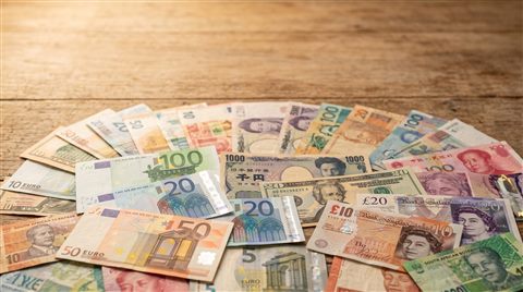 Photorealistic photo of world currency banknotes, wide shot with open space at the top for text, warm golden light, calm mood, 16:9 aspect ratio