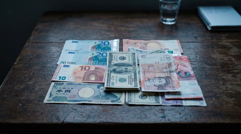 Cinematic film still of world currency banknotes, centered subject with a simple uncluttered composition, cool blue tones, quiet atmosphere, 16:9 aspect ratio