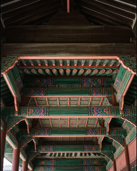 Cinematic film still of a seamless traditional Korean dancheong pattern in red, green and blue, wide shot with open space at the top for text, vivid colors, high contrast, energetic, 4:5 aspect ratio