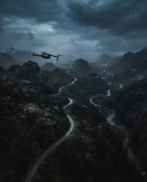 Cinematic film still of a drone flying over a landscape, high-angle view from above, moody dark tones, dramatic lighting, 4:5 aspect ratio