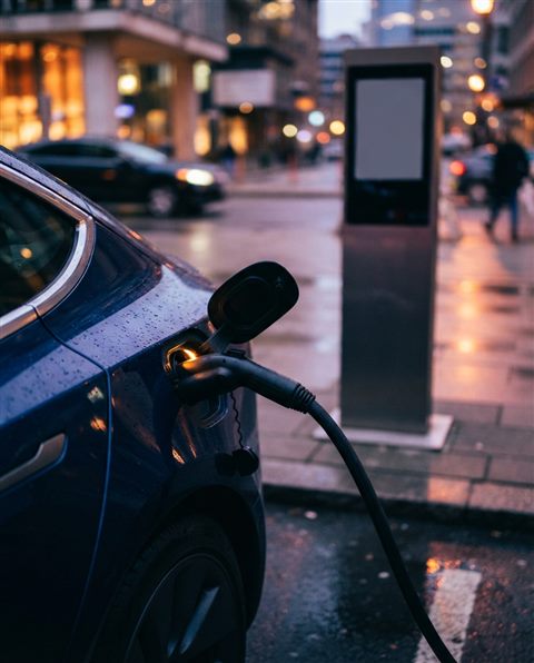 Cinematic film still of an electric car charging at a station, close-up detail with shallow depth of field, vivid colors, high contrast, energetic, 4:5 aspect ratio