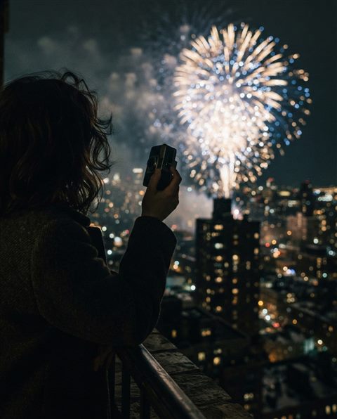 Cinematic film still of fireworks over a city, close-up detail with shallow depth of field, moody dark tones, dramatic lighting, 4:5 aspect ratio