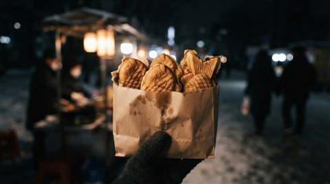 겨울날 종이봉투에 담긴 붕어빵, 사실적인 사진, 단순하고 깔끔한 구도 가운데 놓인 피사체, 어두운 톤, 극적인 조명, 16:9 비율