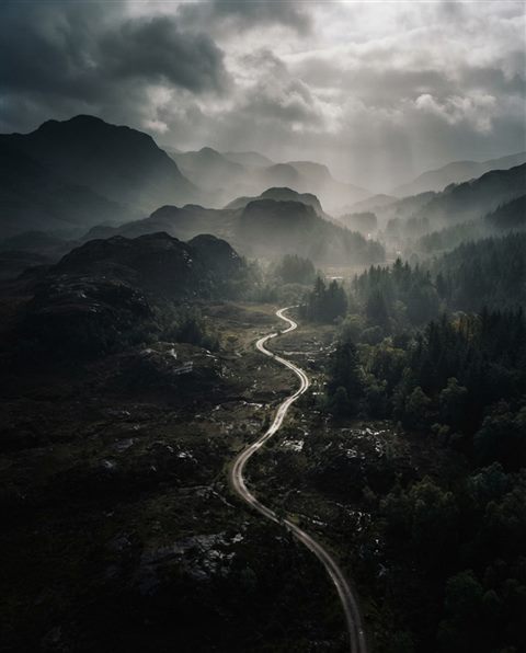 Cinematic film still of foggy landscape, high-angle view from above, moody dark tones, dramatic lighting, 4:5 aspect ratio