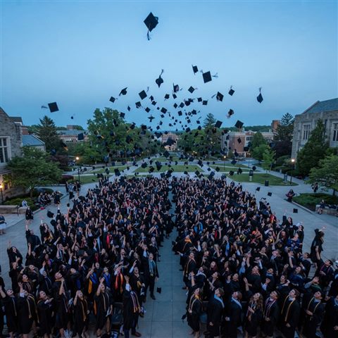 Photorealistic photo of graduation caps tossed into the sky, high-angle view from above, cool blue tones, quiet atmosphere, 1:1 aspect ratio