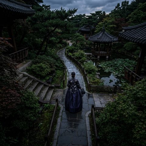 Photorealistic photo of a fictional woman wearing a traditional korean hanbok in a palace garden, high-angle view from above, moody dark tones, dramatic lighting, 1:1 aspect ratio