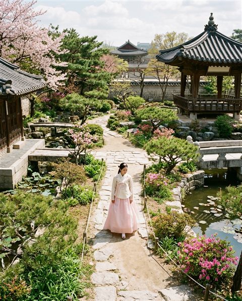 Cinematic film still of a fictional woman wearing a traditional korean hanbok in a palace garden, high-angle view from above, soft pastel colors, bright and cozy, 4:5 aspect ratio