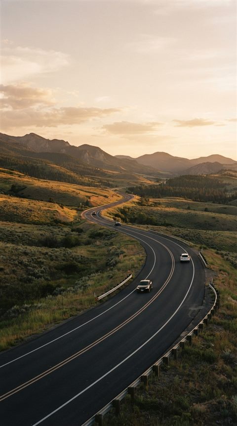 Cinematic film still of a highway winding through hills, wide shot with open space at the top for text, warm golden light, calm mood, 9:16 aspect ratio