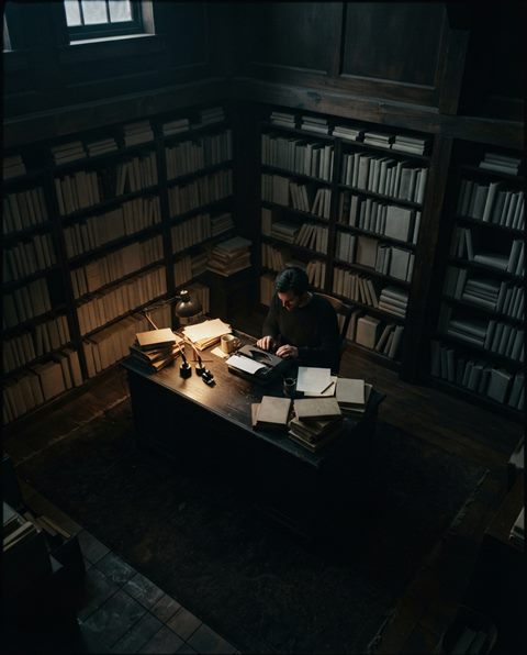 Cinematic film still of a home study room with bookshelves, high-angle view from above, moody dark tones, dramatic lighting, 4:5 aspect ratio