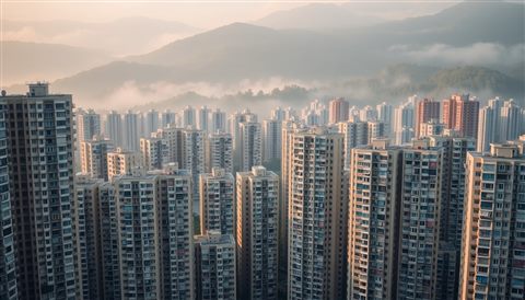 Photorealistic photo of Dense high-rise apartment buildings tightly packed against a misty mountain background, high-angle view from above, warm golden light, calm mood, 16:9 aspect ratio