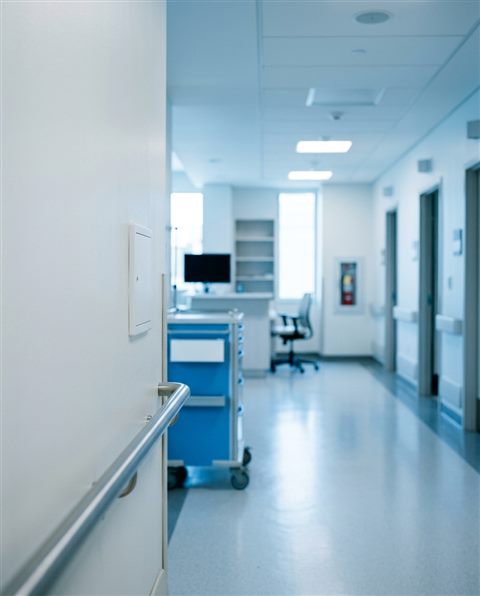 Cinematic film still of a clean modern hospital corridor, close-up detail with shallow depth of field, cool blue tones, quiet atmosphere, 4:5 aspect ratio