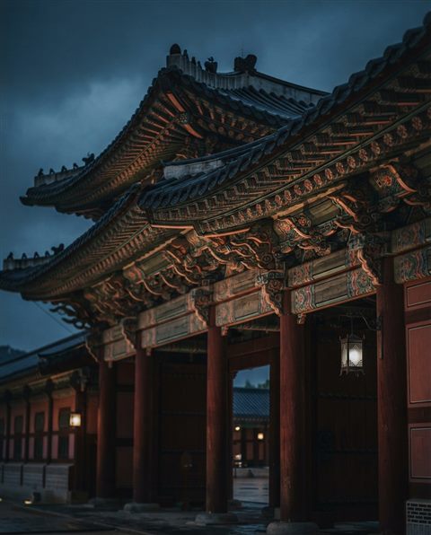 Photorealistic photo of a grand traditional Korean palace gate with colorful dancheong patterns, close-up detail with shallow depth of field, moody dark tones, dramatic lighting, 4:5 aspect ratio