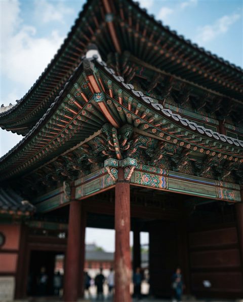 Cinematic film still of a grand traditional Korean palace gate with colorful dancheong patterns, close-up detail with shallow depth of field, vivid colors, high contrast, energetic, 4:5 aspect ratio
