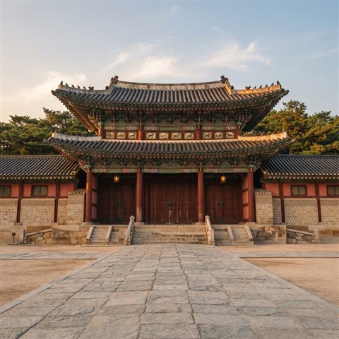 Photorealistic photo of a grand traditional Korean palace gate with colorful dancheong patterns, centered subject with a simple uncluttered composition, warm golden light, calm mood, 1:1 aspect ratio