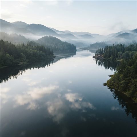 Photorealistic photo of calm lake reflecting the sky, high-angle view from above, misty morning haze, dreamy, 1:1 aspect ratio