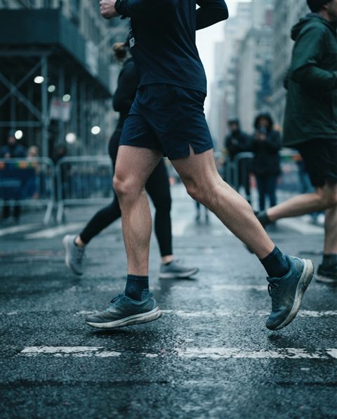 Cinematic film still of runners in a city marathon, close-up detail with shallow depth of field, cool blue tones, quiet atmosphere, 4:5 aspect ratio