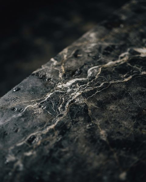 Cinematic film still of marble texture, close-up detail with shallow depth of field, moody dark tones, dramatic lighting, 4:5 aspect ratio