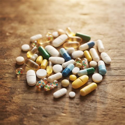 Photorealistic photo of pills and capsules, high-angle view from above, warm golden light, calm mood, 1:1 aspect ratio