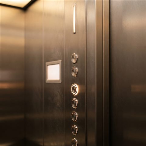 Photorealistic photo of interior of a modern sleek stainless steel elevator with illuminated buttons, close-up detail with shallow depth of field, warm golden light, calm mood, 1:1 aspect ratio