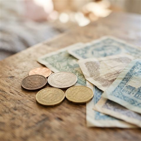 Photorealistic photo of coins and banknotes, close-up detail with shallow depth of field, soft pastel colors, bright and cozy, 1:1 aspect ratio