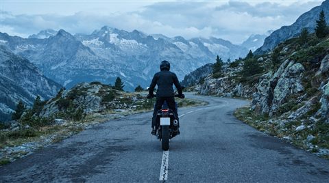 Photorealistic photo of a motorcycle on a mountain road, centered subject with a simple uncluttered composition, cool blue tones, quiet atmosphere, 16:9 aspect ratio