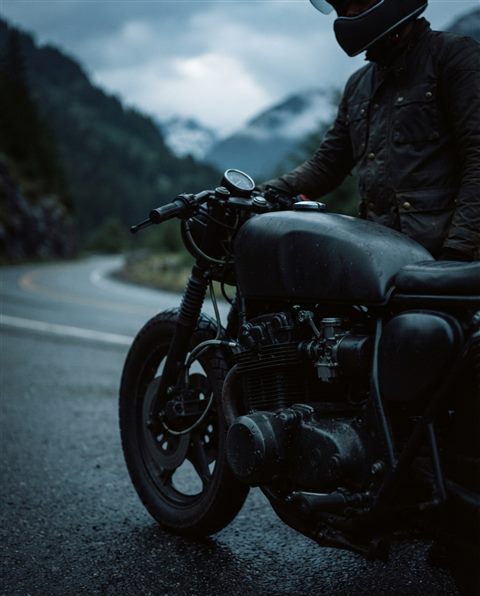 Cinematic film still of a motorcycle on a mountain road, close-up detail with shallow depth of field, moody dark tones, dramatic lighting, 4:5 aspect ratio