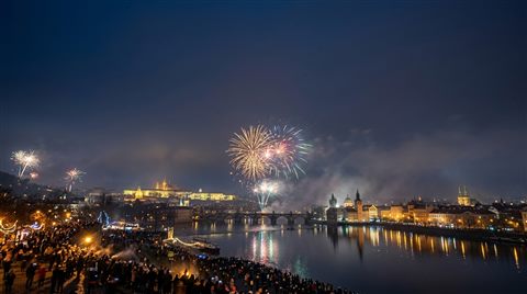 Photorealistic photo of new year celebration with fireworks, wide shot with open space at the top for text, misty morning haze, dreamy, 16:9 aspect ratio