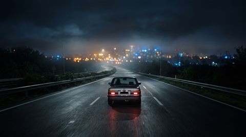 Cinematic film still of car driving on an empty highway at night with city lights, centered subject with a simple uncluttered composition, misty morning haze, dreamy, 16:9 aspect ratio