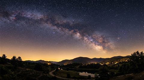 Photorealistic photo of starry night sky, wide shot with open space at the top for text, warm golden light, calm mood, 16:9 aspect ratio